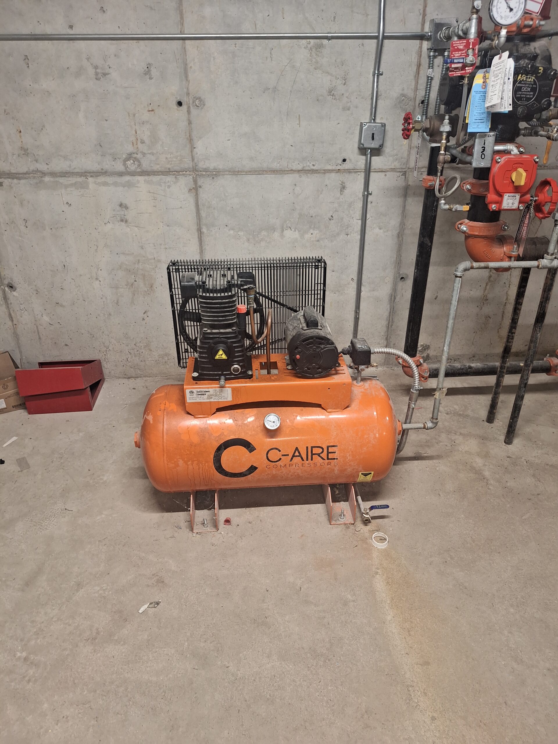 A large orange commercial electric fire pump and piping system installed inside a facility pump room.